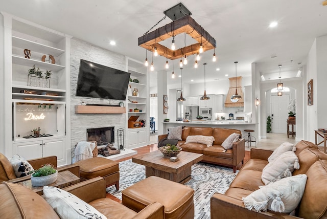 living room featuring built in shelves, a fireplace, and light hardwood / wood-style floors