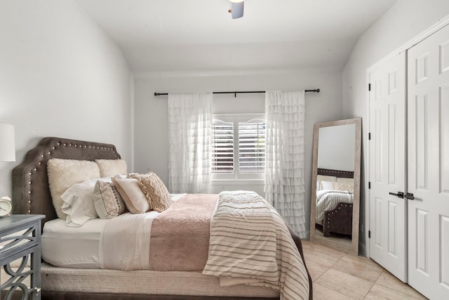 bedroom featuring ceiling fan, light tile patterned floors, a closet, and vaulted ceiling