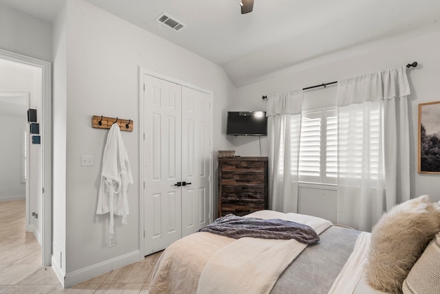 bedroom with lofted ceiling, a closet, light tile patterned flooring, and ceiling fan