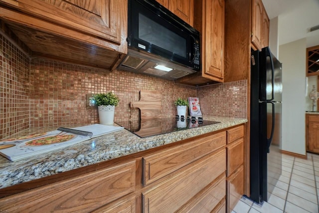 kitchen with black appliances, light tile patterned flooring, light stone countertops, and tasteful backsplash