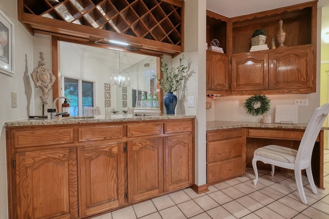 kitchen with light stone countertops, light tile patterned floors, decorative light fixtures, and an inviting chandelier