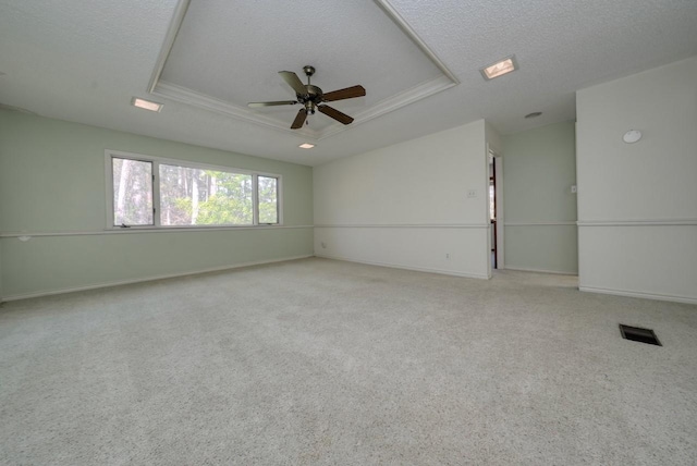 unfurnished room with a tray ceiling, ceiling fan, crown molding, and light colored carpet