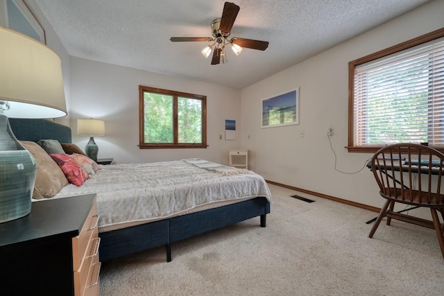 bedroom featuring light carpet, ceiling fan, and a textured ceiling