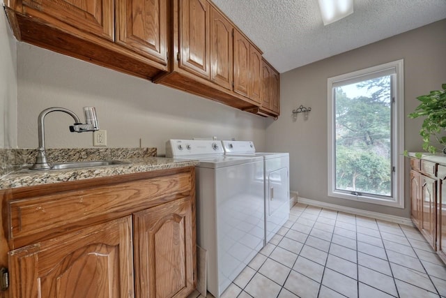 laundry area with a textured ceiling, washing machine and dryer, a healthy amount of sunlight, and sink