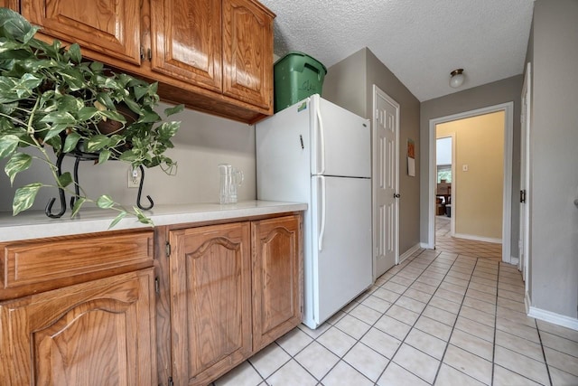 kitchen featuring white fridge, light tile patterned flooring, and a textured ceiling