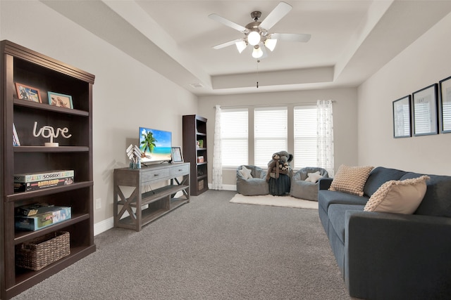 carpeted living room featuring ceiling fan and a tray ceiling