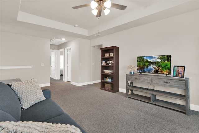 carpeted living room with ceiling fan and a raised ceiling