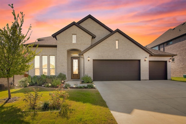 french country home featuring a garage and a yard