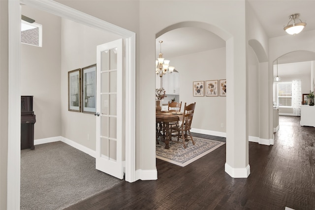 corridor with dark wood-type flooring and a notable chandelier