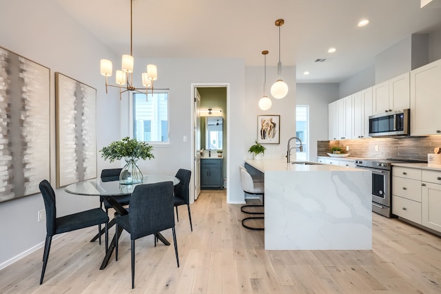 kitchen with decorative light fixtures, sink, appliances with stainless steel finishes, and tasteful backsplash