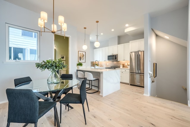 dining area featuring light hardwood / wood-style floors, a notable chandelier, and sink