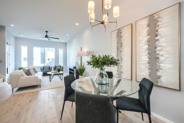 dining room with light hardwood / wood-style floors and ceiling fan with notable chandelier