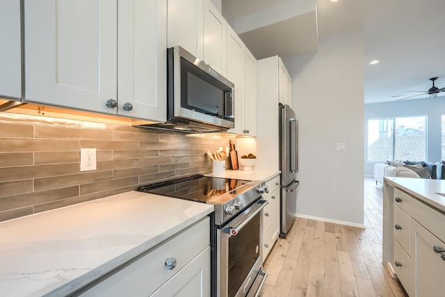 kitchen featuring white cabinets, decorative backsplash, light wood-type flooring, light stone counters, and stainless steel appliances