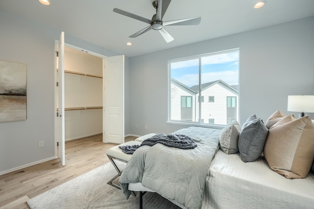 bedroom featuring ceiling fan, light wood-type flooring, a walk in closet, and a closet