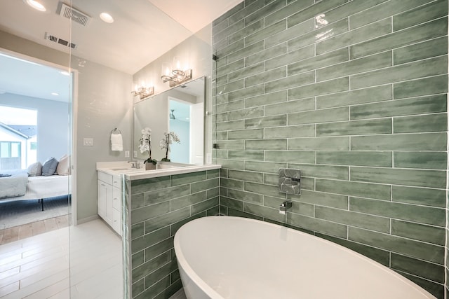 bathroom featuring tile patterned floors, a bathing tub, vanity, and tile walls