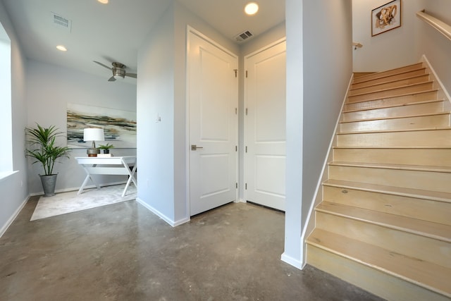 stairway with concrete floors and ceiling fan