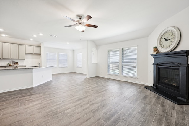 unfurnished living room with ceiling fan, hardwood / wood-style flooring, and sink