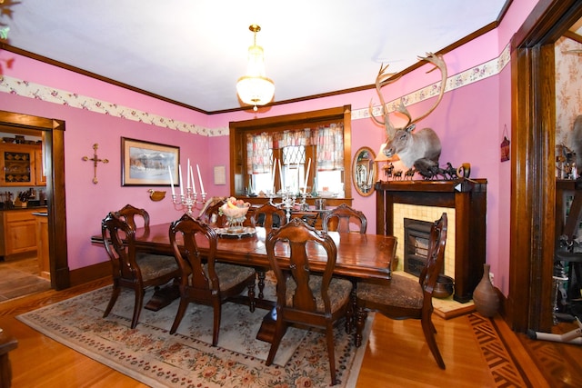 dining space featuring ornamental molding, hardwood / wood-style flooring, and a fireplace