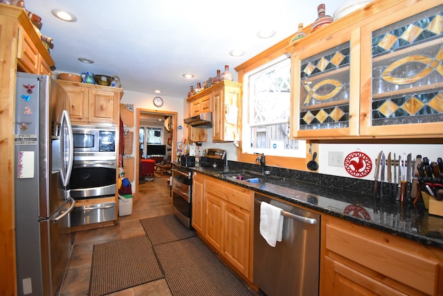 kitchen with stainless steel appliances, dark stone counters, sink, and dark tile patterned flooring