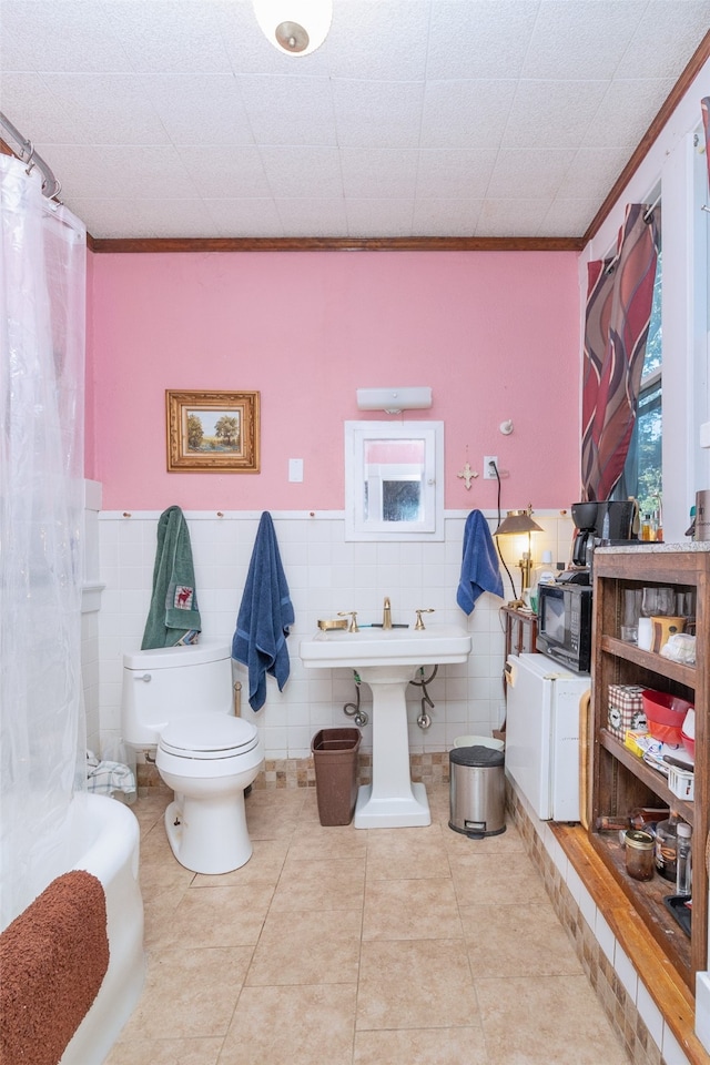 bathroom featuring ornamental molding, tile patterned floors, tile walls, and toilet