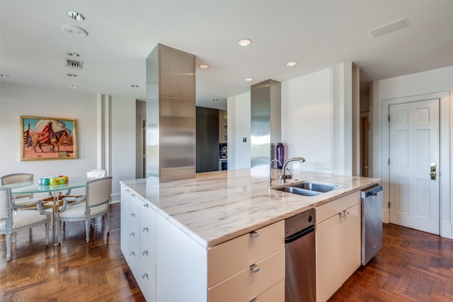 kitchen with light stone counters, an island with sink, sink, white cabinetry, and dishwasher