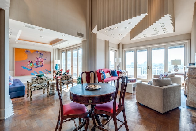 dining room featuring a raised ceiling, dark parquet floors, and a healthy amount of sunlight