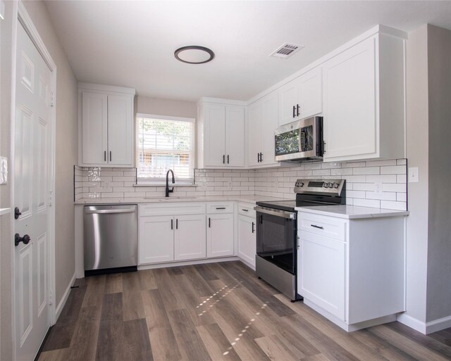 kitchen with white cabinetry, backsplash, electric range, and light wood-type flooring