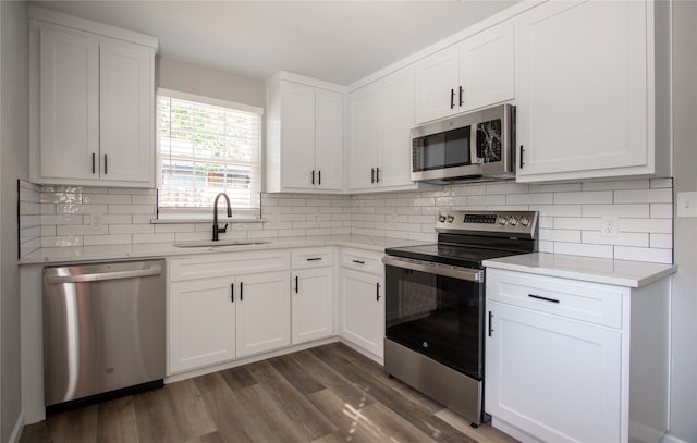 kitchen with decorative backsplash, dark hardwood / wood-style flooring, white cabinetry, sink, and stainless steel appliances