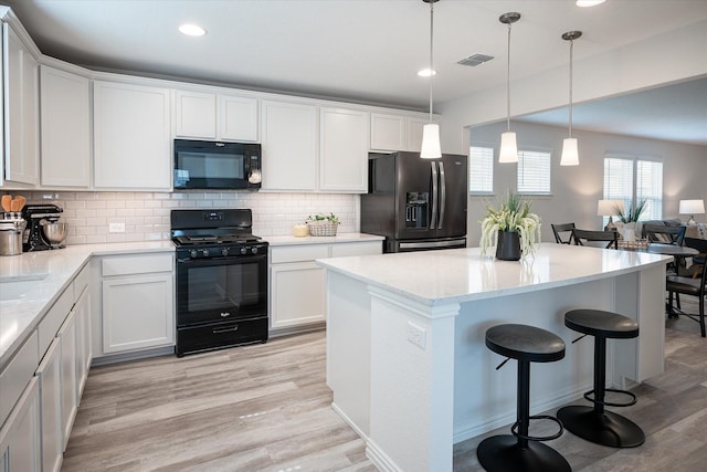 kitchen with tasteful backsplash, sink, black appliances, white cabinetry, and hanging light fixtures