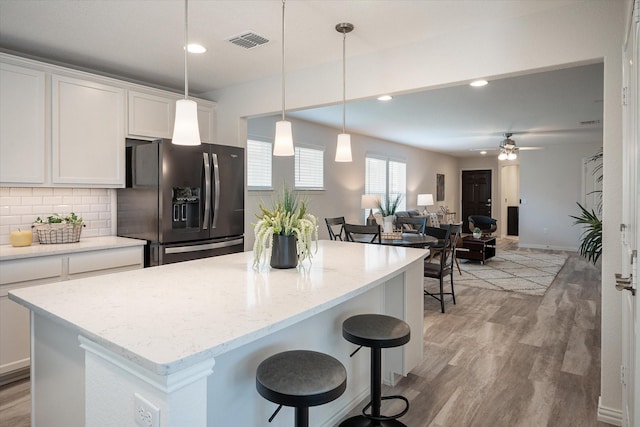 kitchen with white cabinetry, sink, light stone counters, light hardwood / wood-style floors, and black appliances