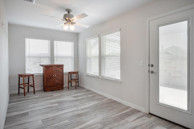 kitchen with a center island, hanging light fixtures, light hardwood / wood-style flooring, ceiling fan, and light stone counters