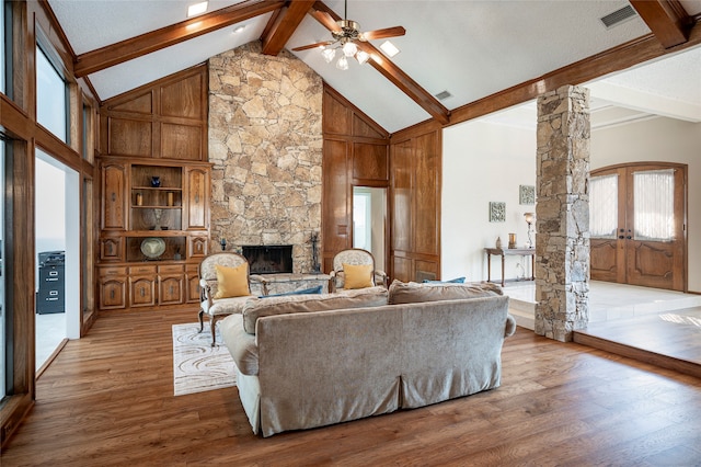 living room with ornate columns, wood-type flooring, high vaulted ceiling, and a wealth of natural light