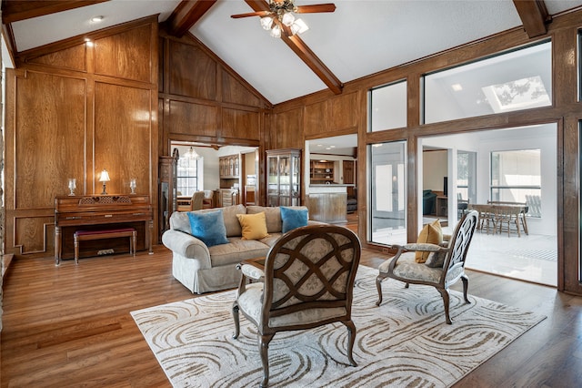 living room with wood-type flooring, high vaulted ceiling, beam ceiling, and ceiling fan