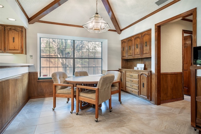 dining room with crown molding, a notable chandelier, wooden walls, vaulted ceiling with beams, and a textured ceiling