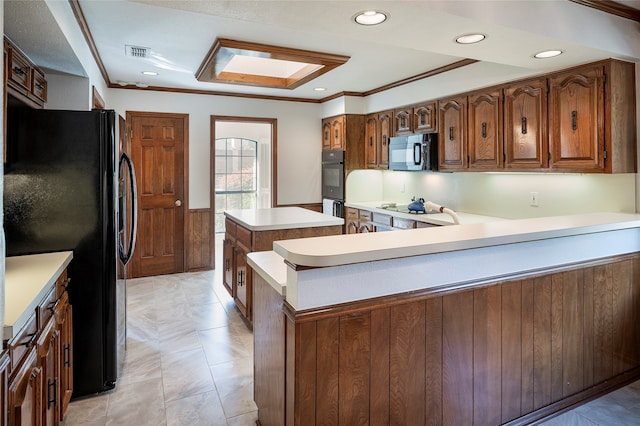 kitchen featuring a skylight, kitchen peninsula, black appliances, and ornamental molding