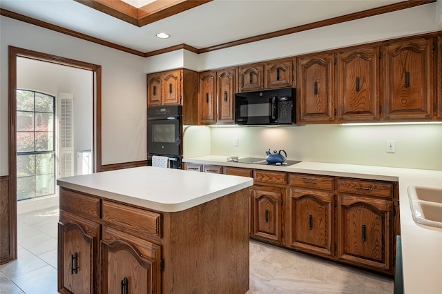 kitchen featuring ornamental molding, black appliances, sink, and a center island