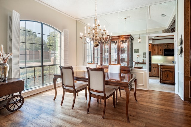 dining room featuring crown molding, a chandelier, light hardwood / wood-style floors, and a textured ceiling