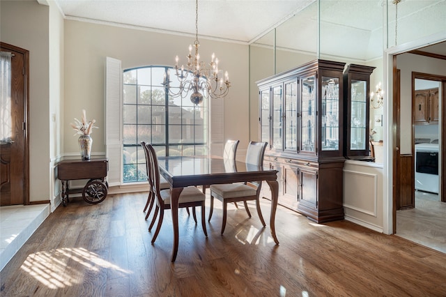 dining space featuring washer / clothes dryer, an inviting chandelier, hardwood / wood-style floors, and ornamental molding