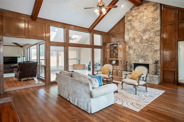 living room featuring a stone fireplace, beamed ceiling, hardwood / wood-style flooring, and ceiling fan