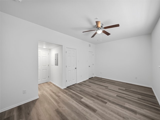 unfurnished bedroom with electric panel, hardwood / wood-style flooring, and ceiling fan