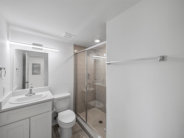 bathroom featuring vanity, toilet, a textured ceiling, and an enclosed shower