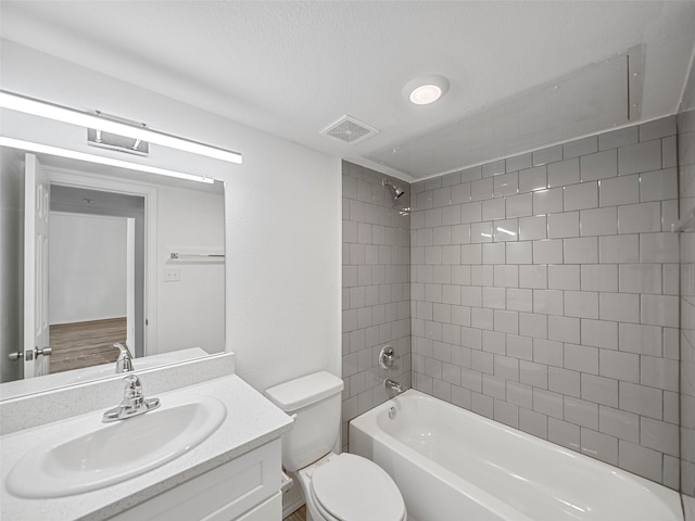 full bathroom featuring tiled shower / bath, vanity, a textured ceiling, and toilet