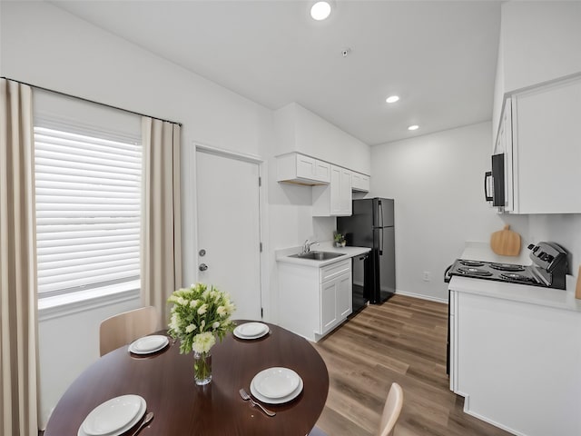 kitchen featuring sink, black appliances, white cabinetry, and dark hardwood / wood-style floors