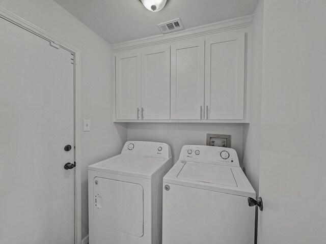 laundry room featuring independent washer and dryer, a textured ceiling, and cabinets