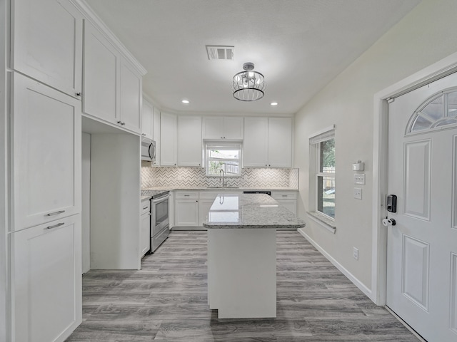 kitchen with a kitchen island, light hardwood / wood-style flooring, sink, white cabinetry, and appliances with stainless steel finishes