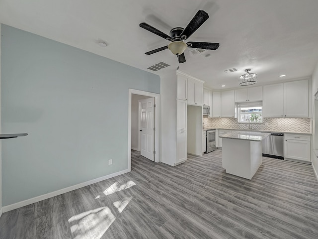 kitchen featuring appliances with stainless steel finishes, white cabinetry, light hardwood / wood-style floors, and a kitchen island