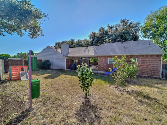 back of property featuring central AC unit and a lawn