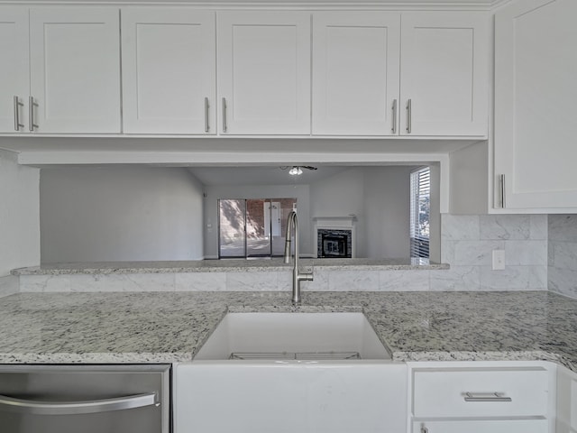 kitchen with light stone countertops, sink, white cabinets, and a healthy amount of sunlight