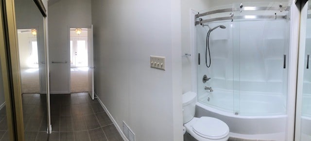 bathroom with combined bath / shower with glass door and toilet