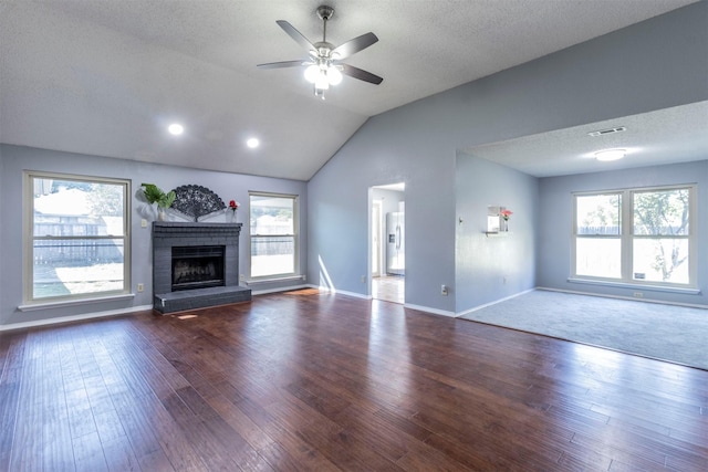 unfurnished living room featuring lofted ceiling, a brick fireplace, hardwood / wood-style flooring, and a textured ceiling